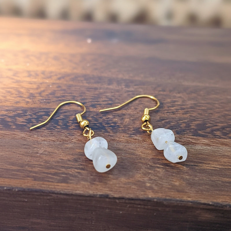 An image displaying a pair of elegant handmade moonstone birthstone earrings with gold-plated hooks, set against a soft background