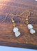 An image displaying a pair of elegant handmade moonstone birthstone earrings with gold-plated hooks, set against a soft background