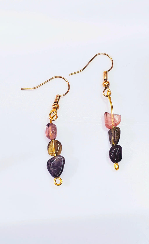 An image displaying a pair of handmade tourmaline three-stone dangle hook earrings featuring black, green, and pink beads, against a soft background, showcasing their vibrant and elegant design.