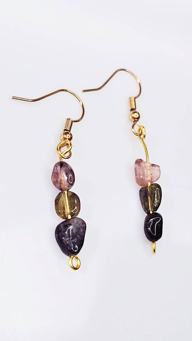 An image showcasing a pair of handcrafted tourmaline three-stone dangle earrings, featuring black, green, and pink tourmaline beads dangling from hook closures, against a neutral background.