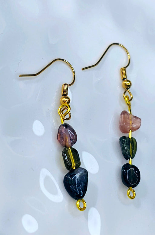 An image displaying a pair of handmade tourmaline three-stone dangle hook earrings, showcasing black, green, and pink tourmaline beads, against a soft background