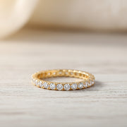 A gold eternity ring with clear round-cut gemstones, shown on a white background with promotional text including 'Adodo Ready to ship' and feature bullet points for nickel-free, eco-friendly, allergy-free, and GRA Certificate.